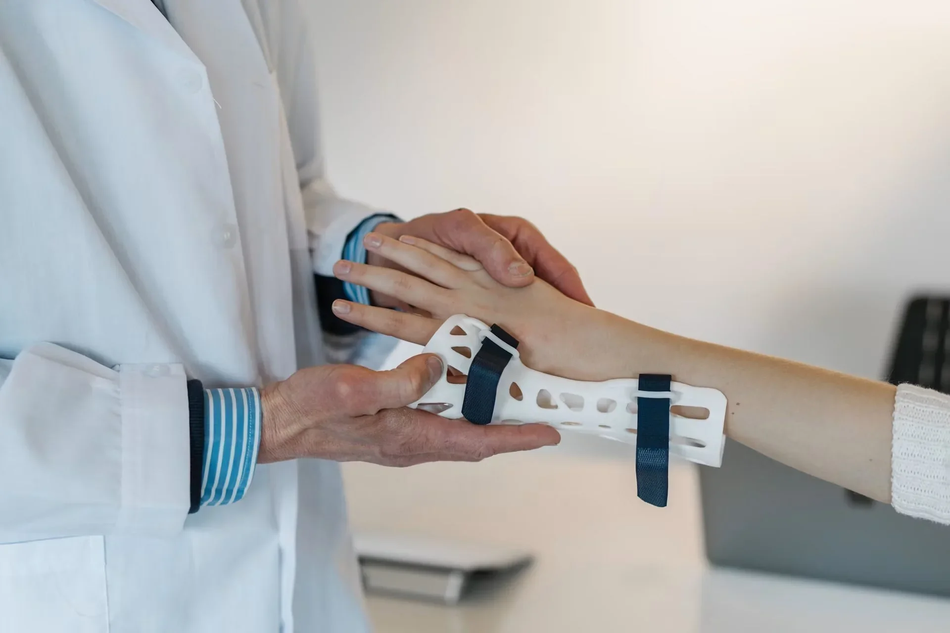 Médico examinando o braço de um paciente com uma órtese de pulso branca e azul